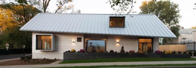 A side view of a prefab home and its gray standing seam roof
