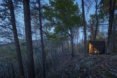 A triangular tiny house in a forest at night
