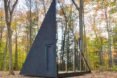 A tiny house shaped like an isosceles triangle with a reflective wall