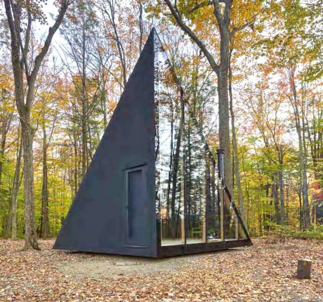 A tiny house shaped like an isosceles triangle with a reflective wall