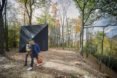 Two people walking in front of a triangular tiny house