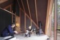 The interior of a tiny house with sloping roofs and two people in chairs