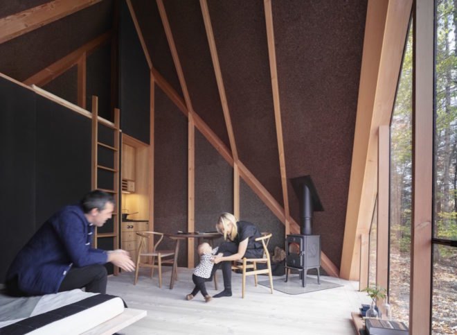 The interior of a tiny house with sloping roofs and two people in chairs
