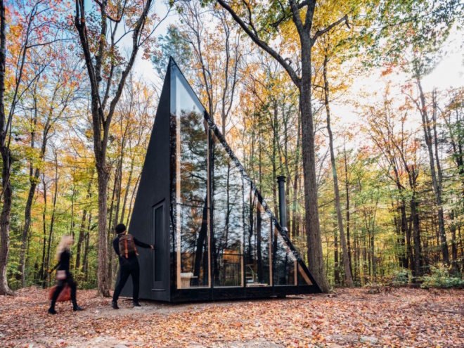 A tiny house shaped like an isosceles triangle with a reflective wall
