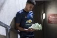 Soccer player wearing Manchester United kit made with recycled plastic and holding a pair of green cleats