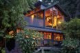 Outside view of the home at dusk, interior warmly glowing from lamps