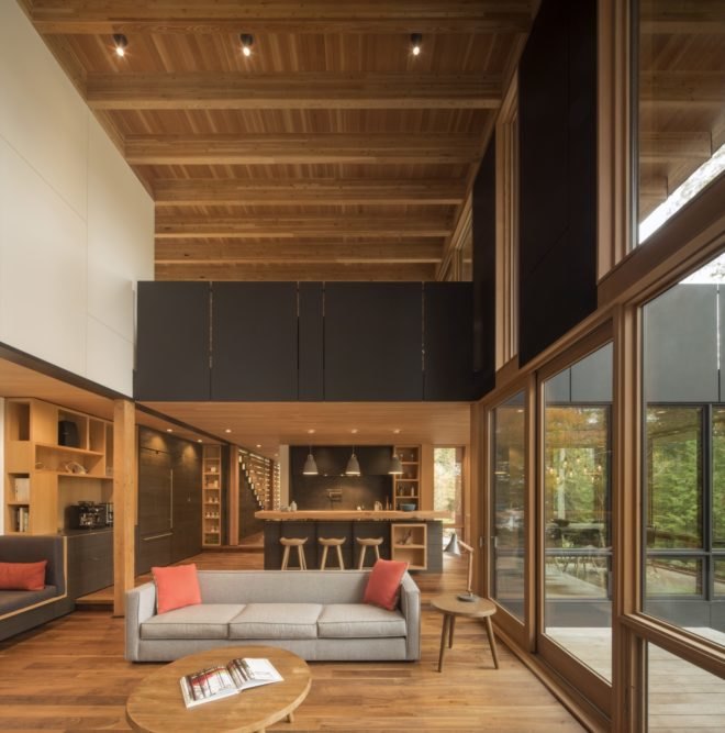 living room has a gray couch and several large glass windows
