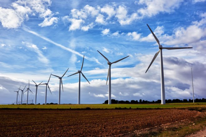 Wind turbines in a field against blue cloudy sky