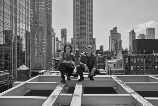 Bjarke Ingels and Adam Neumann in New York City on the frame of a building.