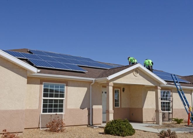 Contractors install solar panels on a home at Edwards Air Force Base in California