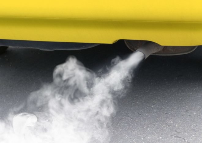 Exhaust, polluting the environment, pours out of a yellow car