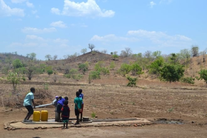 Children in Malawi obtain water from a water pump in a drought-impacted region