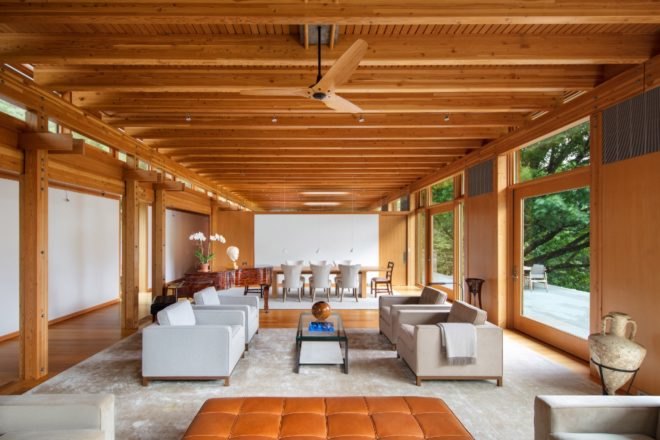 The living room has exposed wooden beams and several floor-to-ceiling windows.