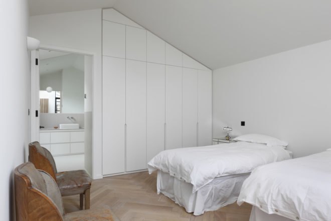 Bedroom with white bedding, white walls and white cabinets