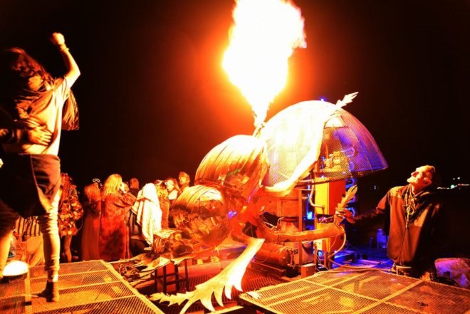 A metal dung beetle shooting flames into the air at night