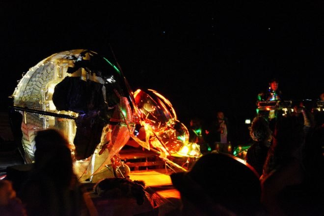 A metal dung beetle sculpture lit up at night