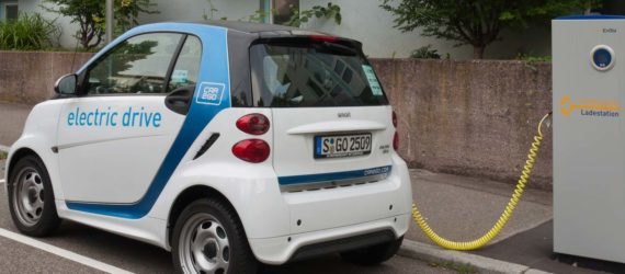 An electric smartcar charging at a curbside power station