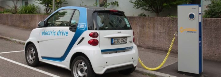 An electric smartcar charging at a curbside power station