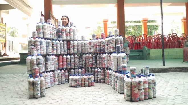 A person stands behind stacked ecobricks