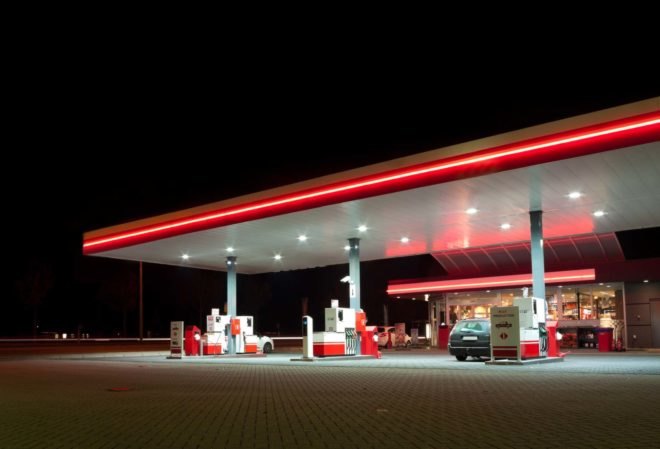 A gas station lit up with red neon at night