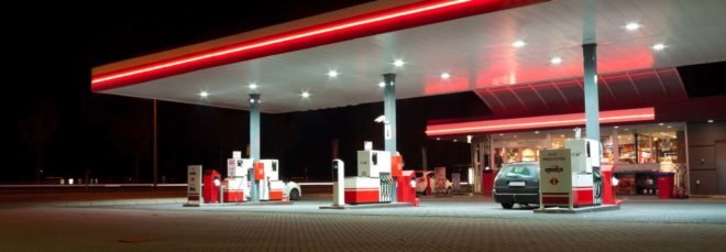A gas station lit up with red neon at night
