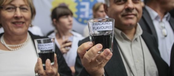 A man and a woman hold fracking-flavored water near the European Parliament