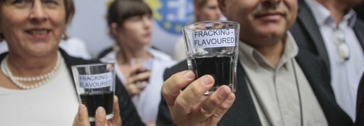 A man and a woman hold fracking-flavored water near the European Parliament