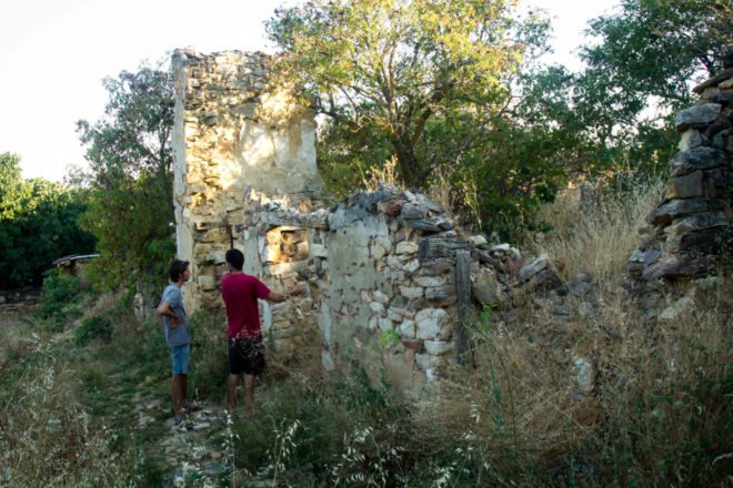 two men standing outside a stone wall