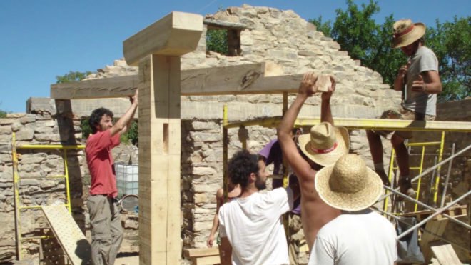 a group of people around a wooden home frame