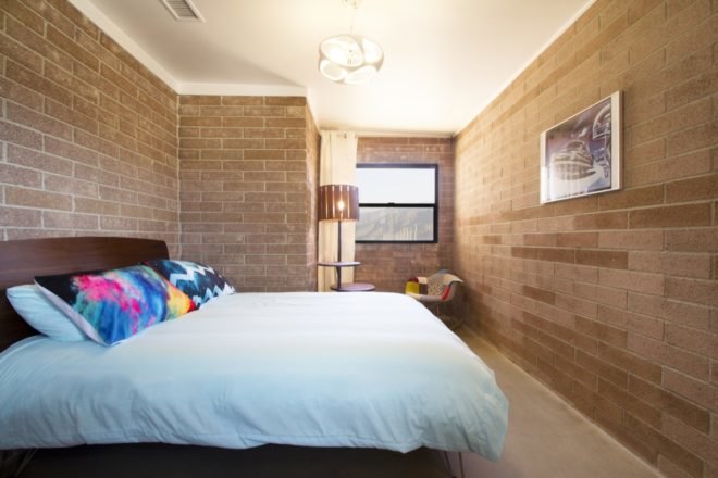 Bedroom has brick walls and bright bedding