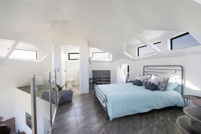 Large bedroom with white walls, blue bedding and plenty of windows
