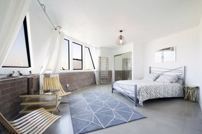 Another bedroom with triangular windows, a patterned area rug and wood furniture