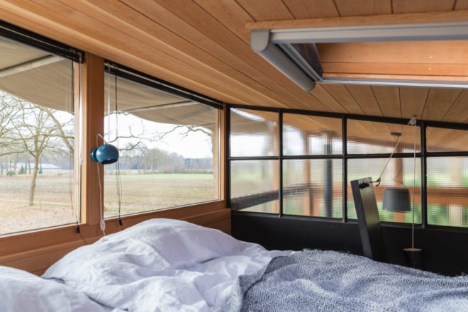 large bed surrounded by windows
