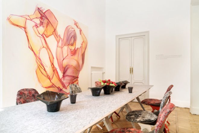 an interior room with a long table and large pieces of art on the walls