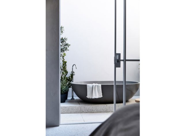 A gray bathtub in front of a white wall.