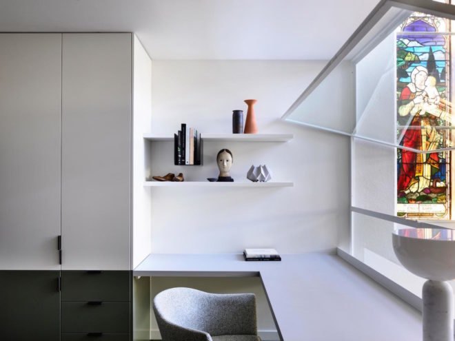 A modern office space with white paneling and a stained glass window.