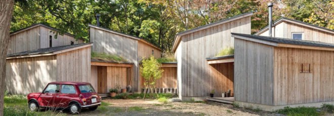 A cluster of wooden cabins in front of blossoming trees.