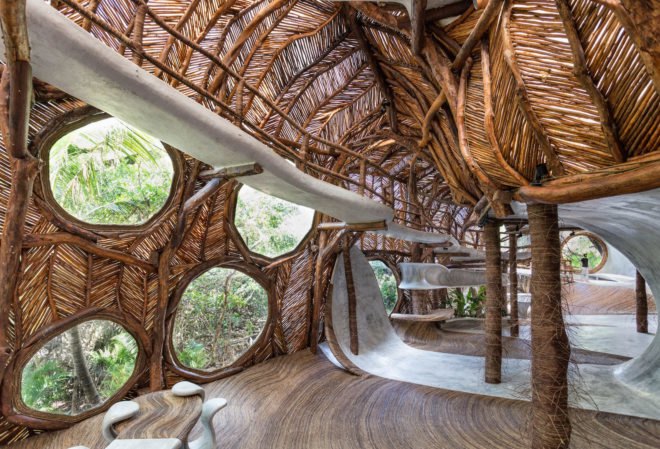 An interior space with round windows and walls made from branches