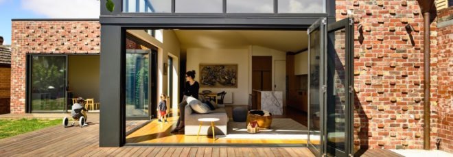A view of a house's furnished interior through a folding glass wall