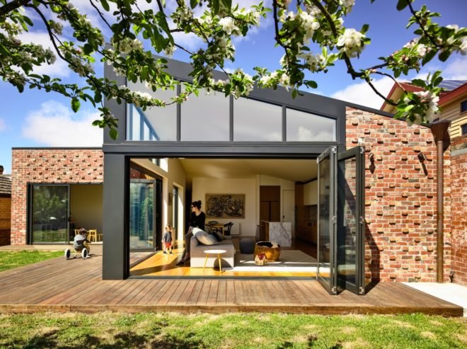 A view of a house's furnished interior through a folding glass wall
