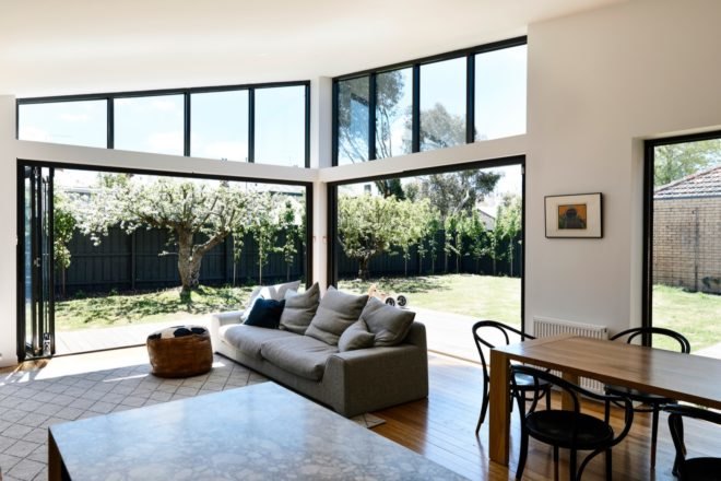 an open plan living room with a sofa and large windows