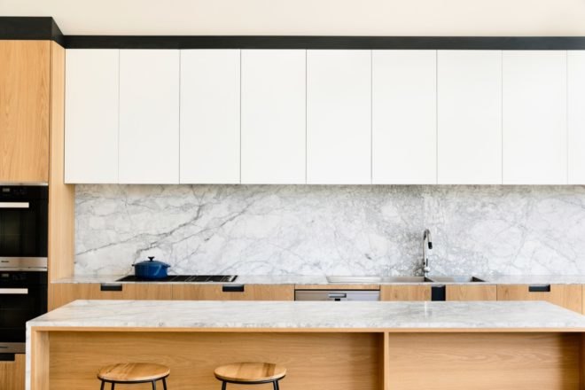 marble counters underneath a row of white kitchen cabinets