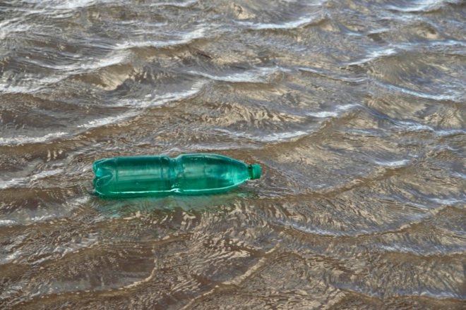 Green plastic bottle floating on water