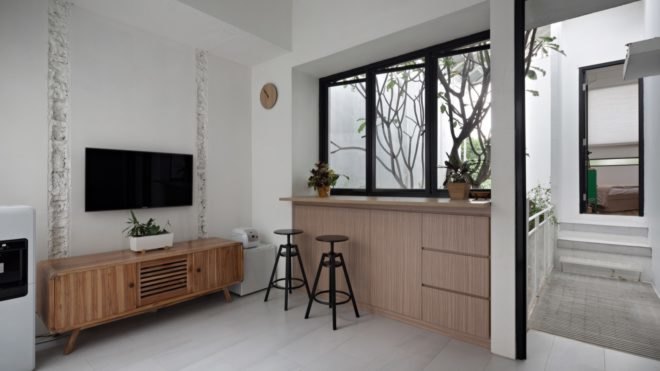 Living area with wall-mounted TV and table and stools facing large windows