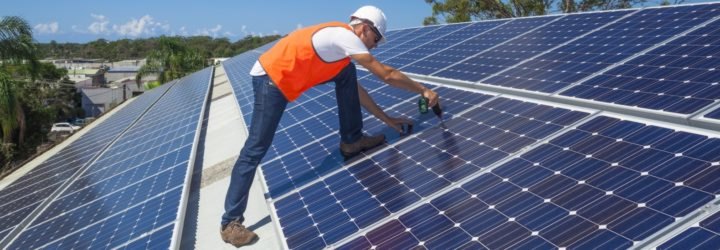 A technician installs solar panels atop a factory roof