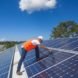 A technician installs solar panels atop a factory roof