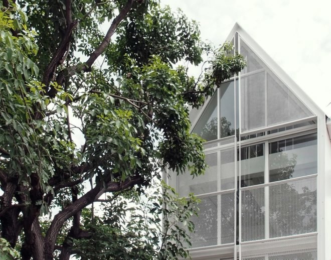 large tree in front of white building with pitched roof
