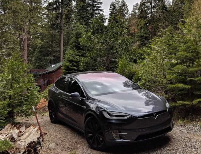 Tesla car amidst the trees, near a cabin in Tahoe