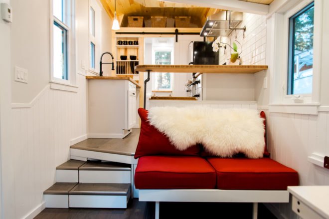 red sofa and stairs leading into a kitchen