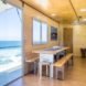 A living room with benches, a table, and an ocean view.